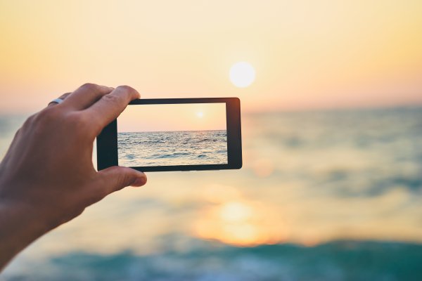 taking photo of sunset on the beach sea smartphone dslr cameras